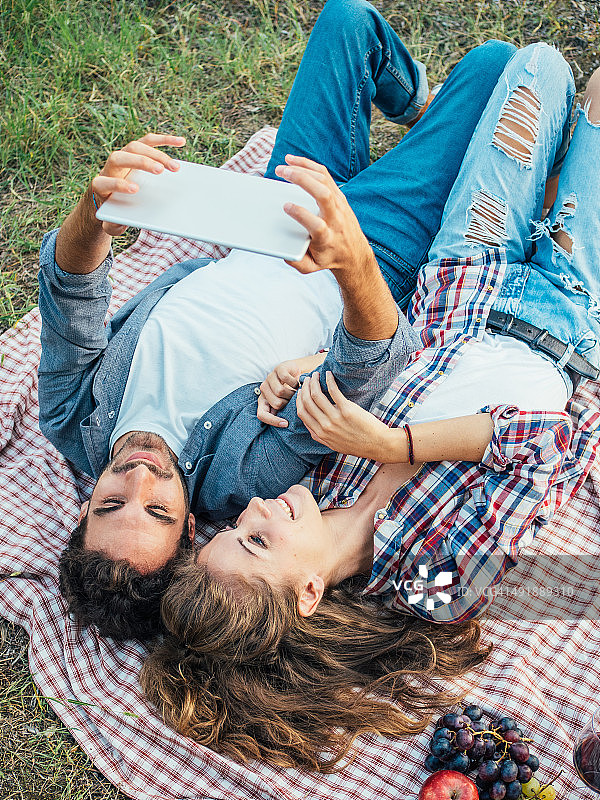 一对年轻夫妇在户外野餐时使用平板电脑图片素材