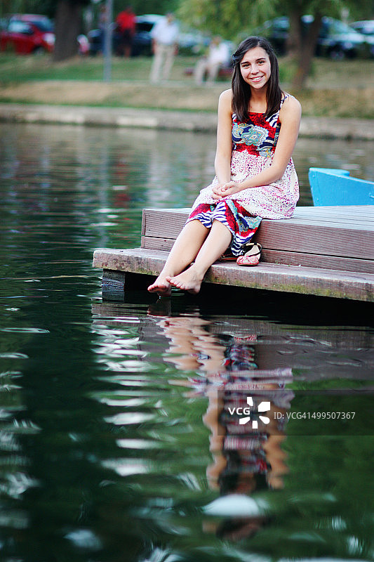 女孩坐在浮筒上，倒影在水中图片素材