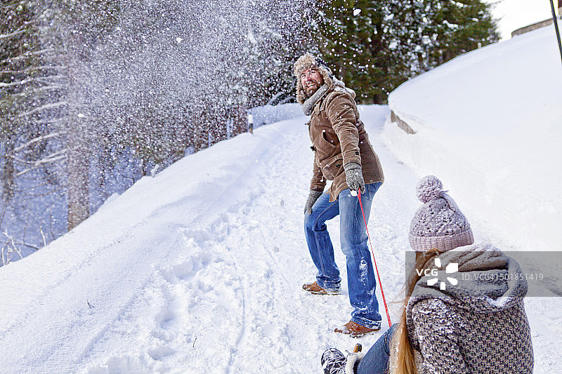 德国巴伐利亚斯皮津斯，男人拉着女人的雪橇图片素材