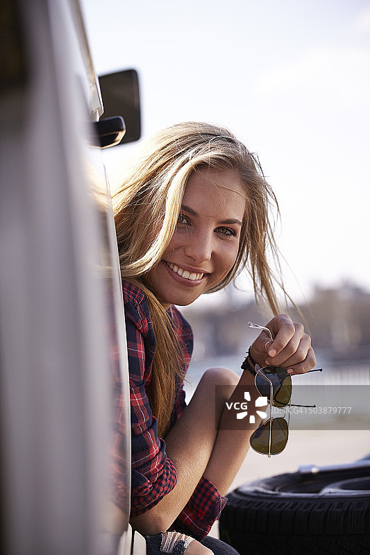 微笑的年轻女子看着小货车图片素材