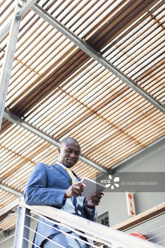 南非开普敦，一名非洲商人站在楼梯上使用数码平板电脑图片素材