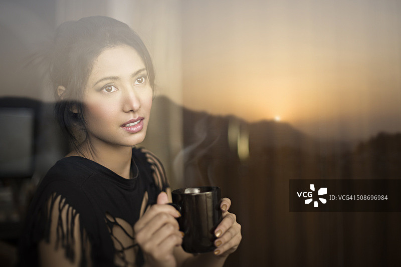 宁静的年轻女子欣赏日出和喝咖啡休息。图片素材