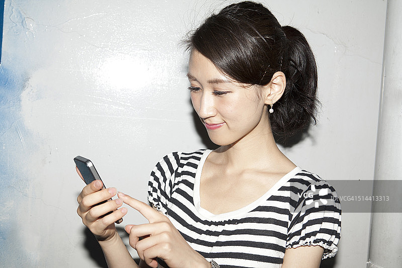 年轻的日本女子用手机，微笑着图片素材