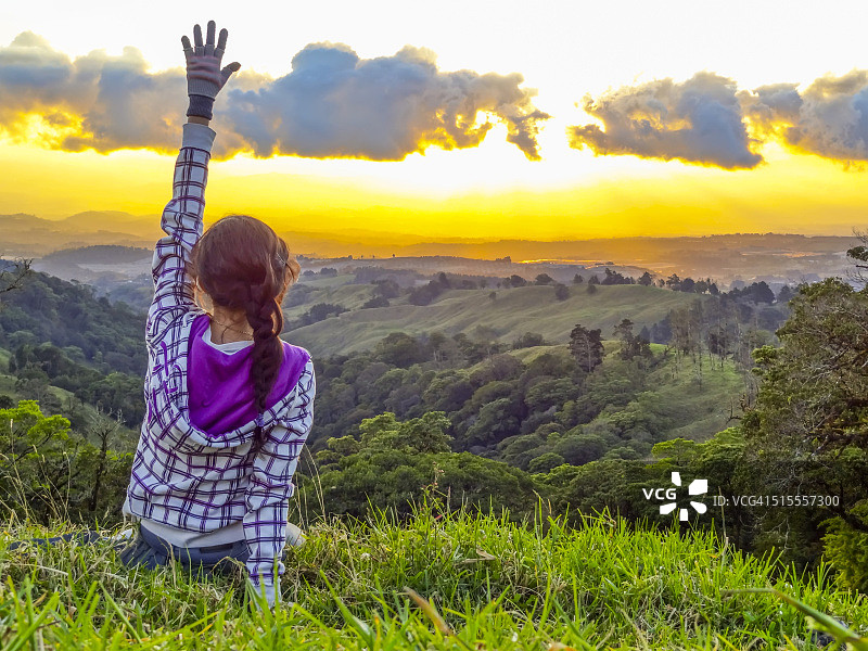 女孩举起手欣赏日落山景图片素材