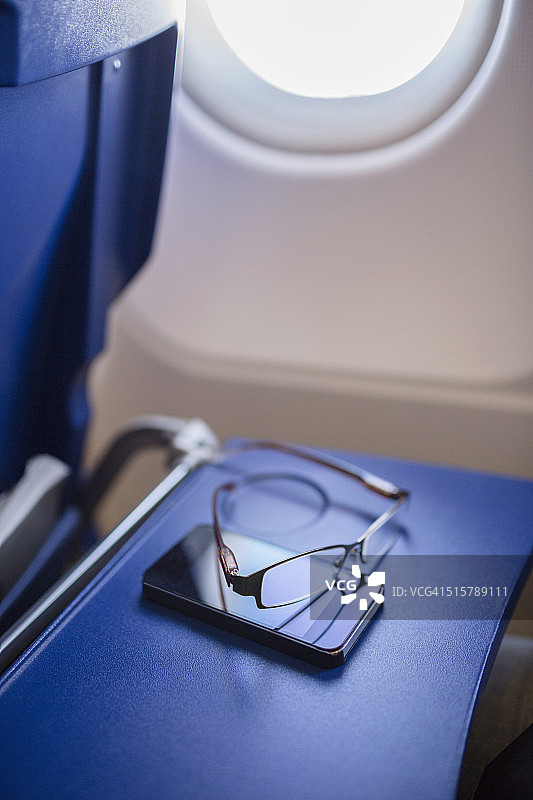 飞机桌上的智能手机和眼镜图片素材