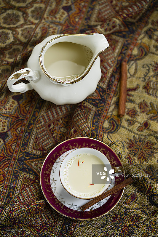 牛奶壶和小咖啡杯豆浆，加藏红花和肉桂在布上调味图片素材