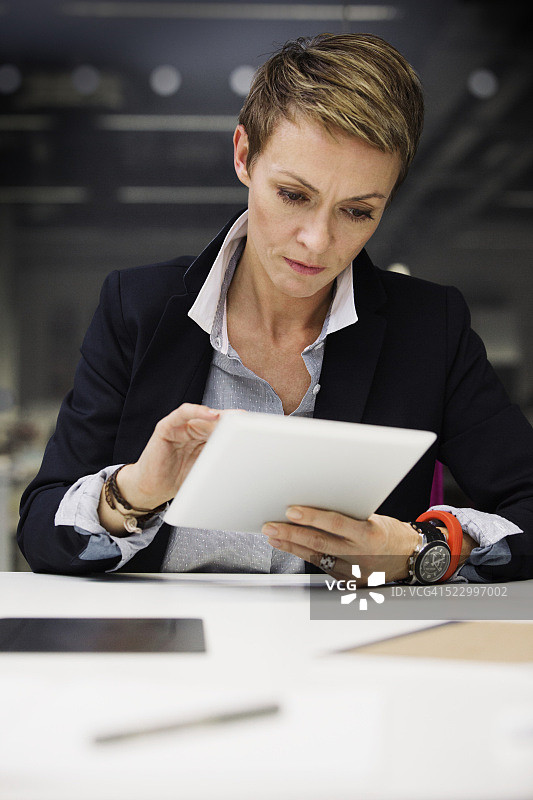 严肃的商业女性在办公桌上使用平板电脑图片素材
