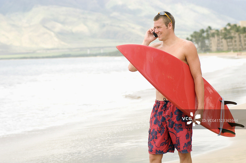 海滩上的冲浪者用手机聊天图片素材