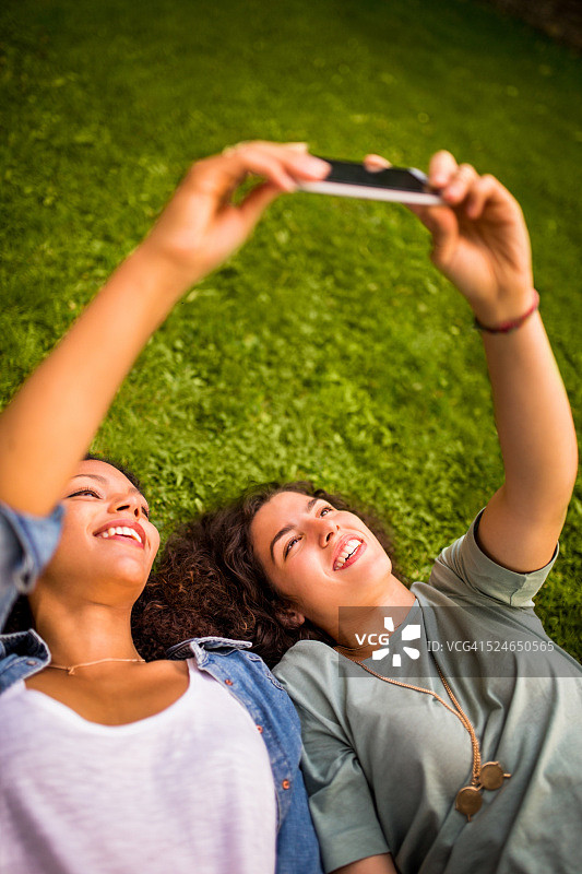 最好的女性朋友一起躺在草地上自拍图片素材