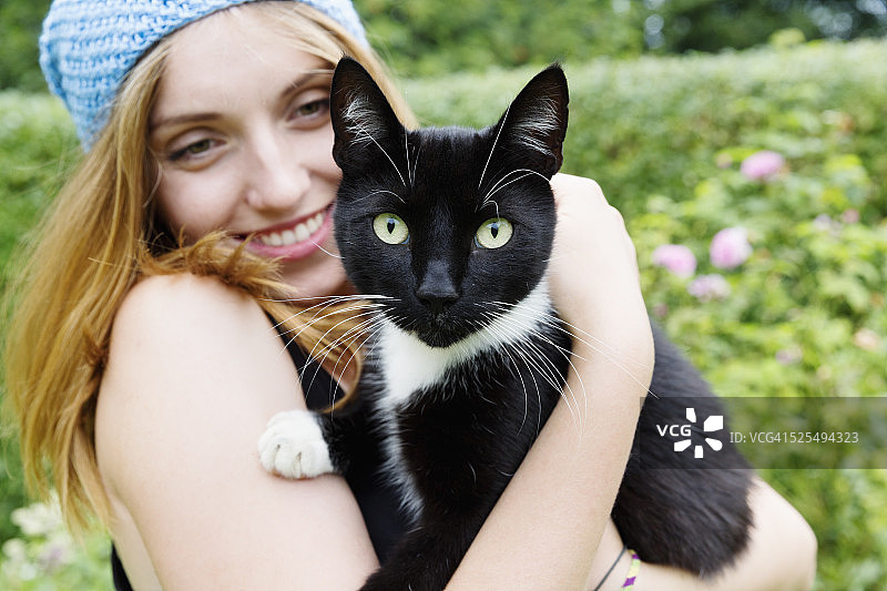 一个微笑的年轻女人的肖像抱在她的胳膊上的猫图片素材