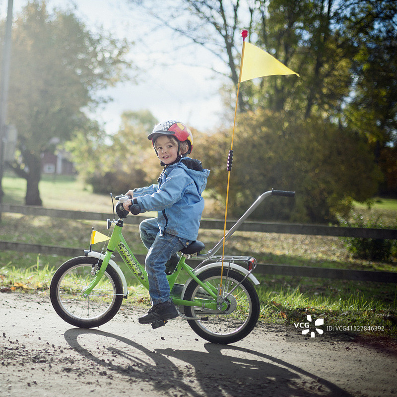 男孩(4-5)在农村的秋天骑自行车图片素材
