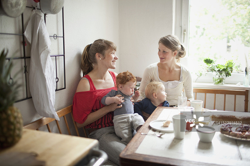 年轻妈妈带着婴儿(6-12个月)在厨房里说话图片素材