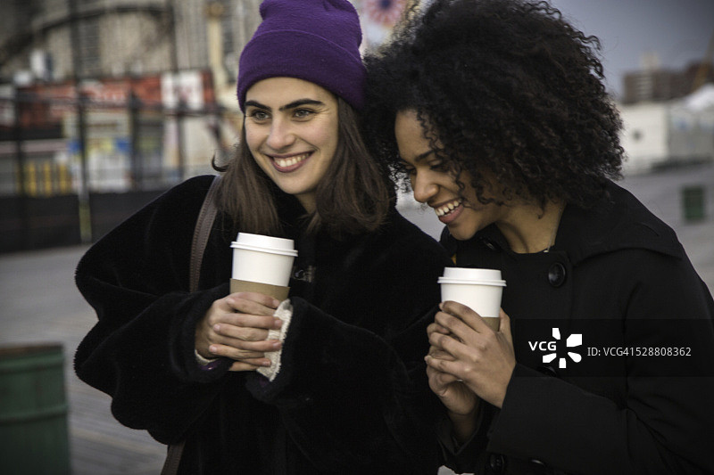 两个女人在木板路上喝咖啡图片素材