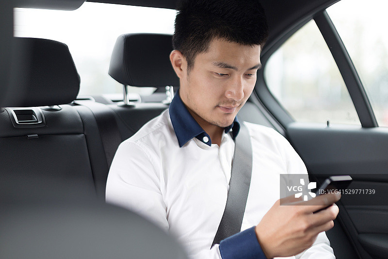 亚洲年轻商人在车里使用智能手机图片素材