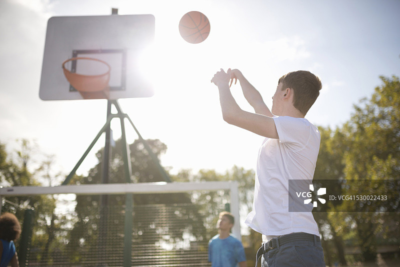年轻的男篮球运动员把篮球扔进篮筐图片素材