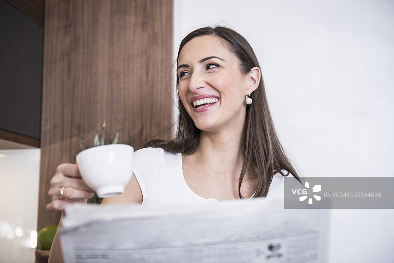 德国巴伐利亚慕尼黑，一名女子边喝咖啡边看报纸图片素材