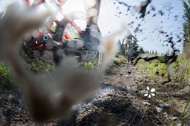 德国萨克森州的矿石山，骑山地自行车的人穿过泥泞的水坑图片素材