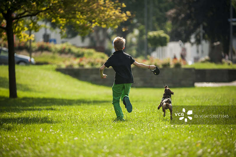 男孩和他的狗在草地上奔跑图片素材