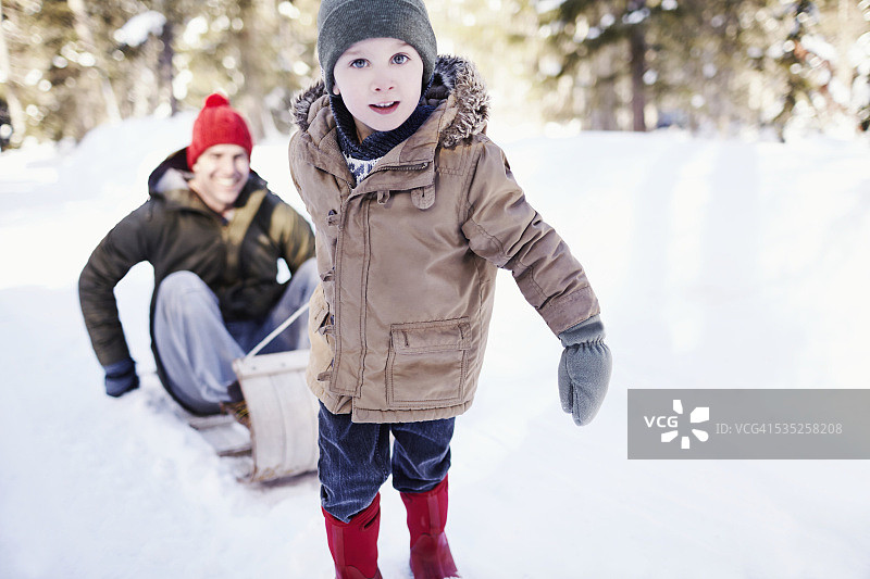 小男孩(4-5岁)拉着父亲(30-34岁)在雪橇上的画像图片素材