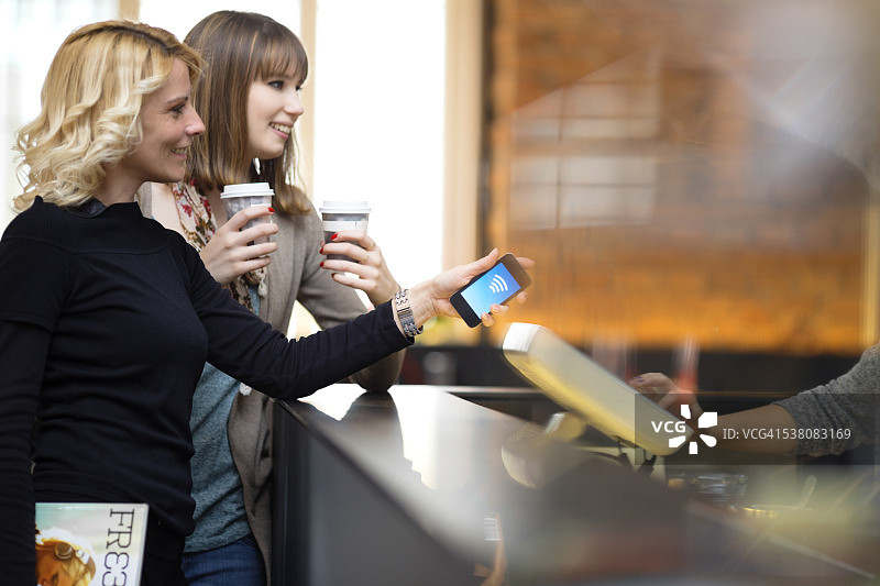 在咖啡吧使用手机进行非接触式支付图片素材