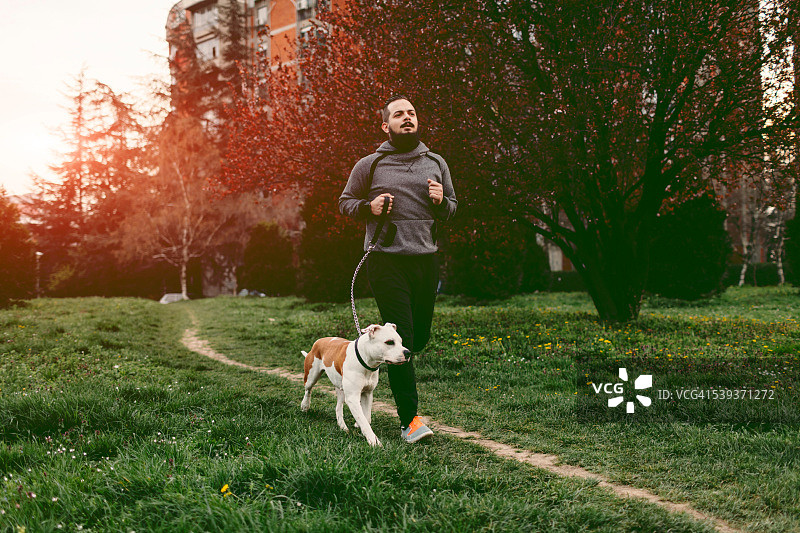 一个人和他的狗一起慢跑。图片素材