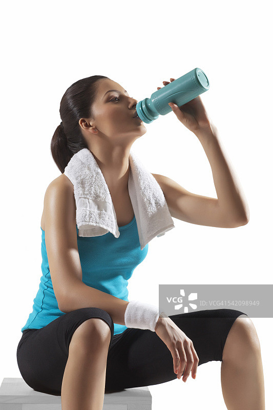 年轻女子饮用瓶装水运动后孤立的白色背景图片素材