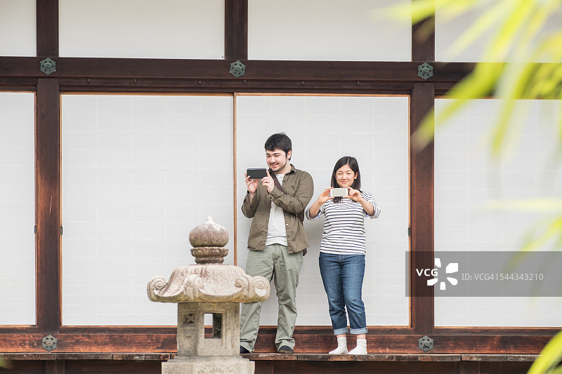 一男一女在日本寺庙用手机拍照图片素材
