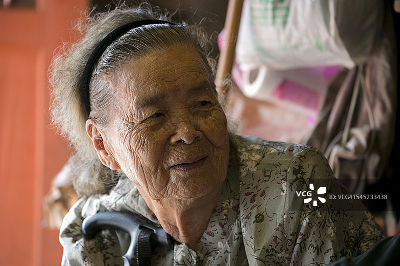 一个年老的亚洲奶奶的肖像，看着左与拐杖图片素材