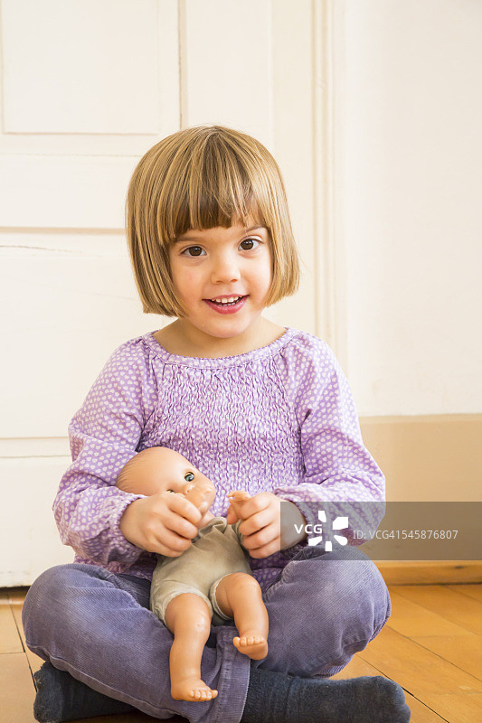 微笑的小女孩玩洋娃娃的肖像图片素材