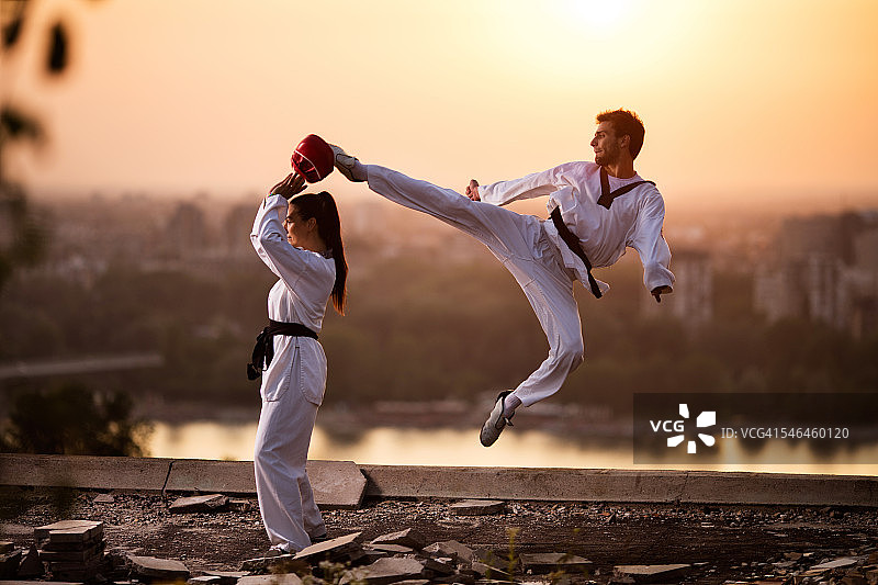 武术家与女性伙伴在日落练习格斗。图片素材