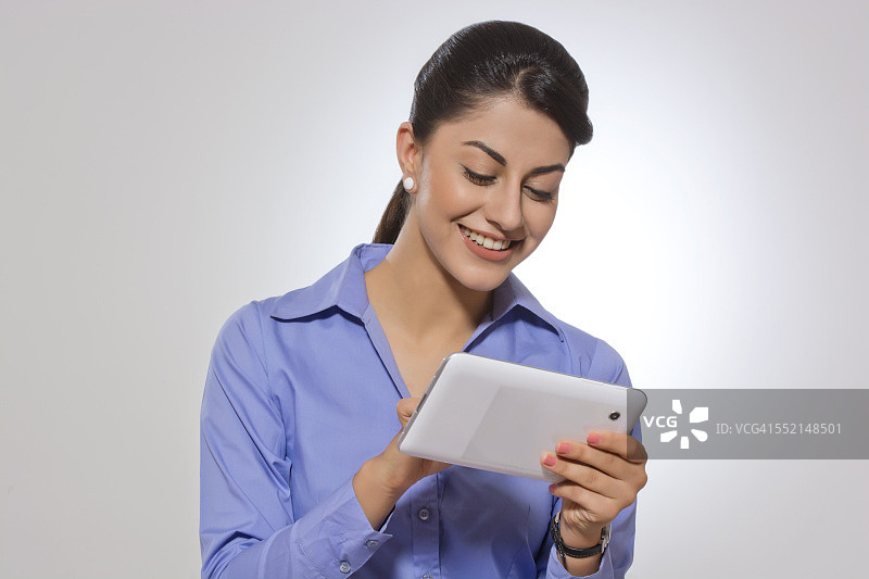 快乐的女商人在灰色的背景下使用平板电脑图片素材