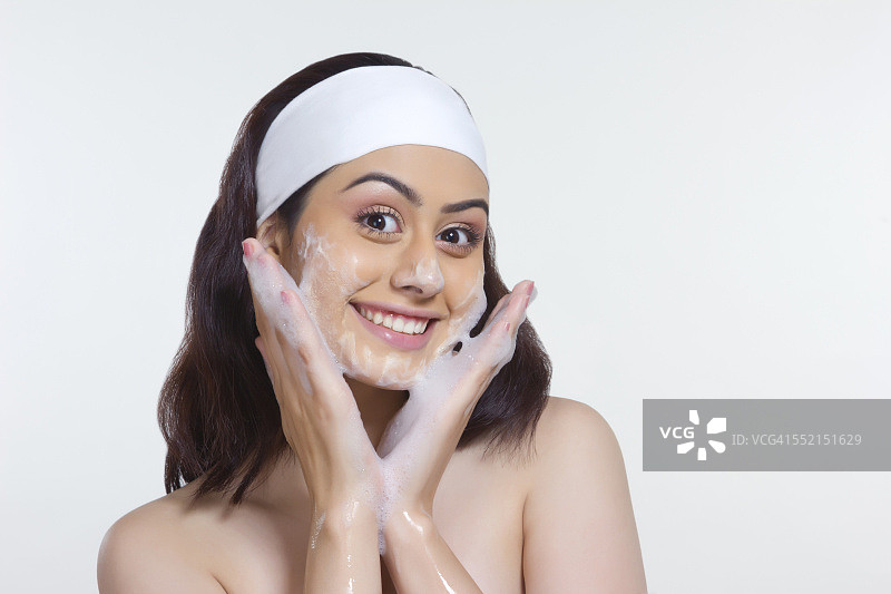 美丽的女人用肥皂擦脸的肖像白色的背景图片素材