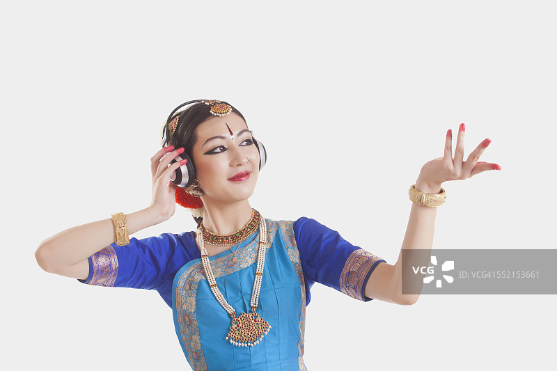 Bharatanatyam舞者戴着耳机在白色背景下表演图片素材