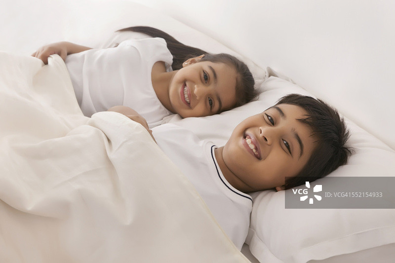 微笑的哥哥和姐姐睡在床上的肖像图片素材