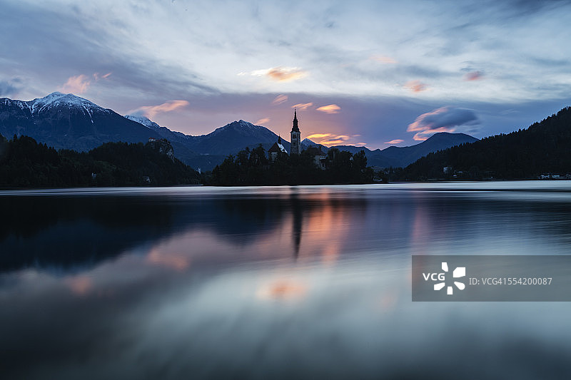 教堂的塔楼和日出的天空倒映在静静的湖面上图片素材