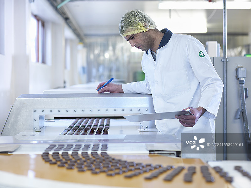 在巧克力工厂生产线上检查巧克力的工人图片素材