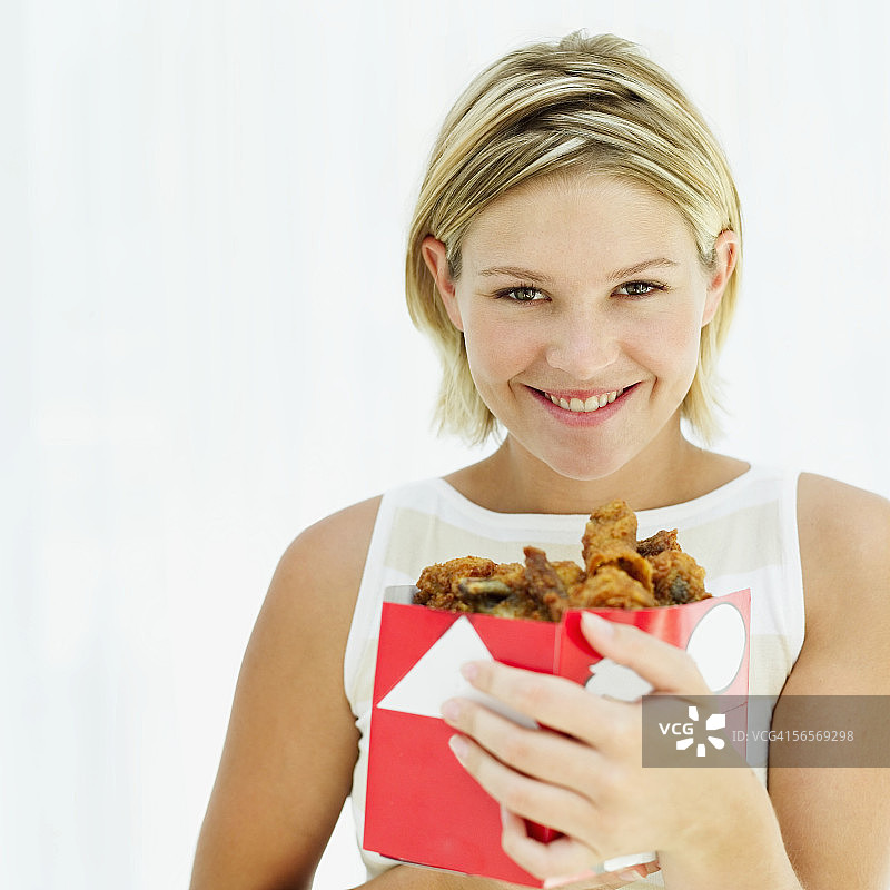 一个年轻女子拿着一盒炸鸡的特写图片素材