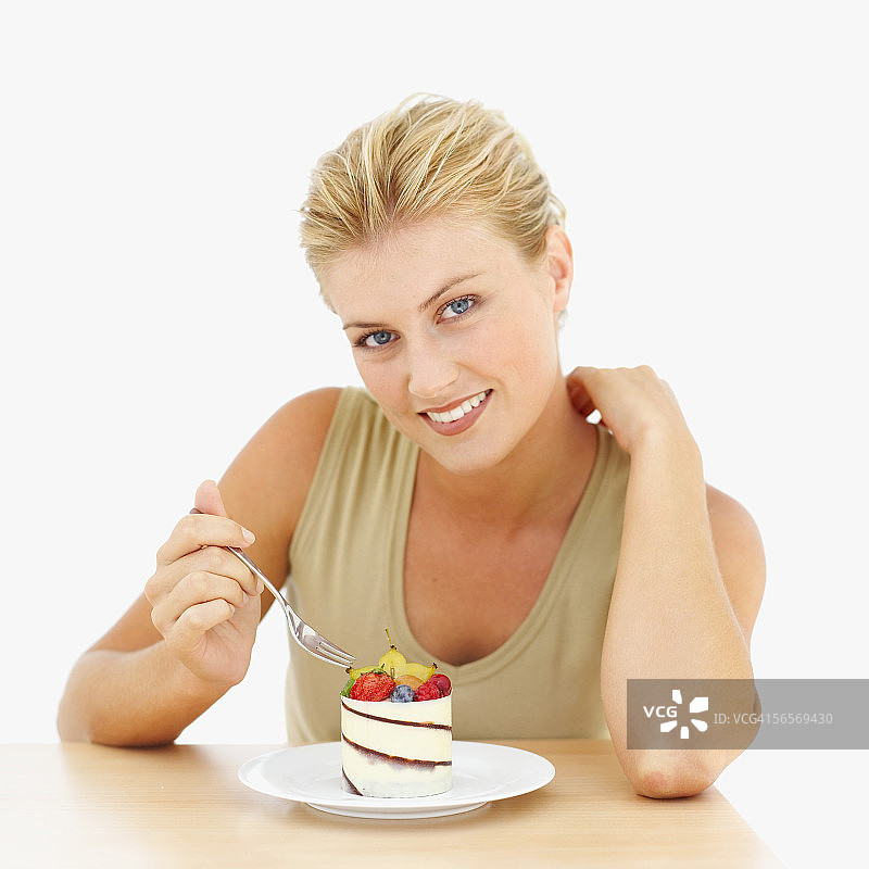 一个年轻女人的肖像举着叉子在一个混合水果糕点图片素材