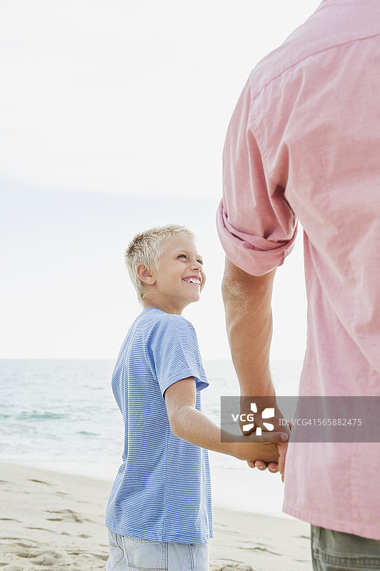 白人父亲和儿子在海滩上牵着手图片素材