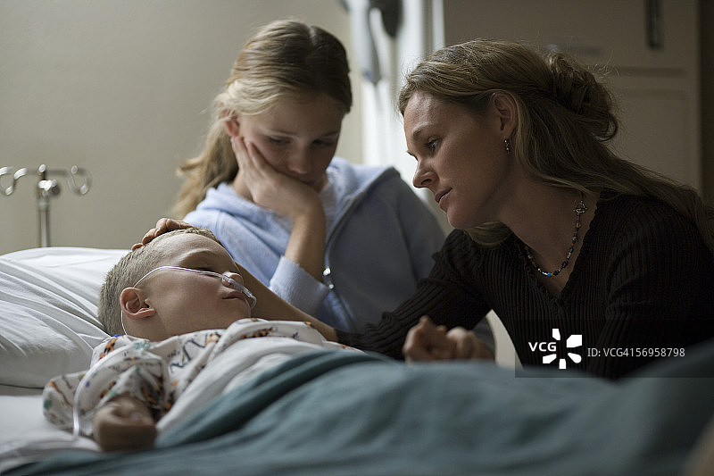 母亲和女儿在医院里安慰儿子图片素材