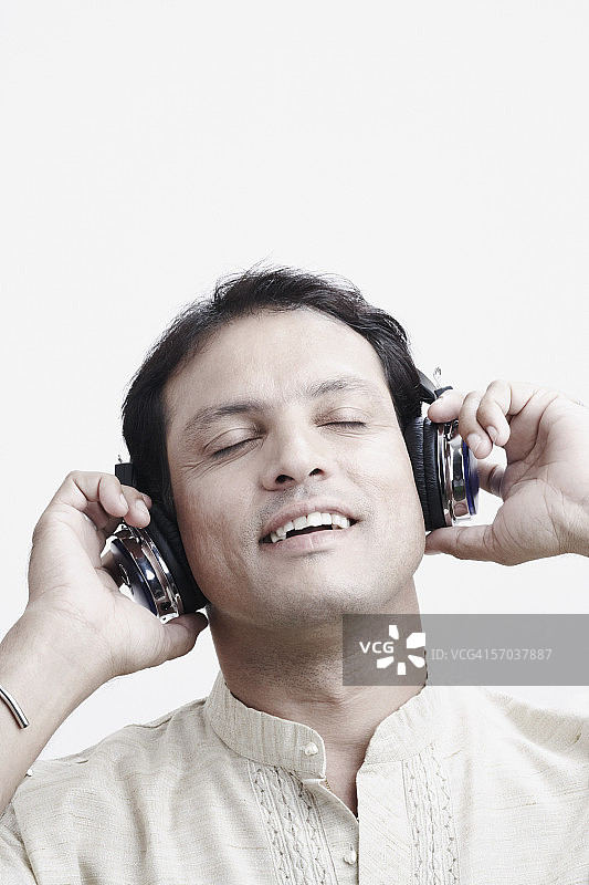一个中年男人戴着耳机听音乐的特写图片素材