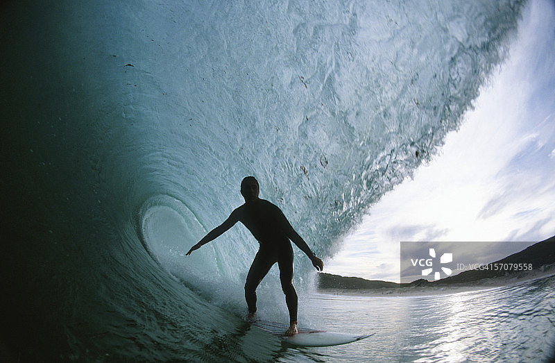 剪影的观点，一个冲浪者骑在一个桶的波浪图片素材