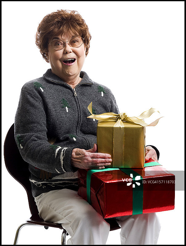 一位年长妇女坐在椅子上拿着礼物的肖像图片素材