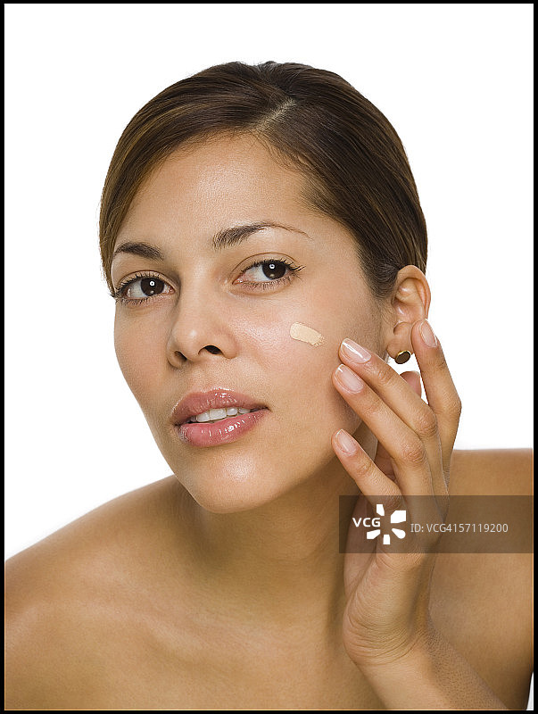 一个女人在她的脸上涂抹保湿霜的特写图片素材