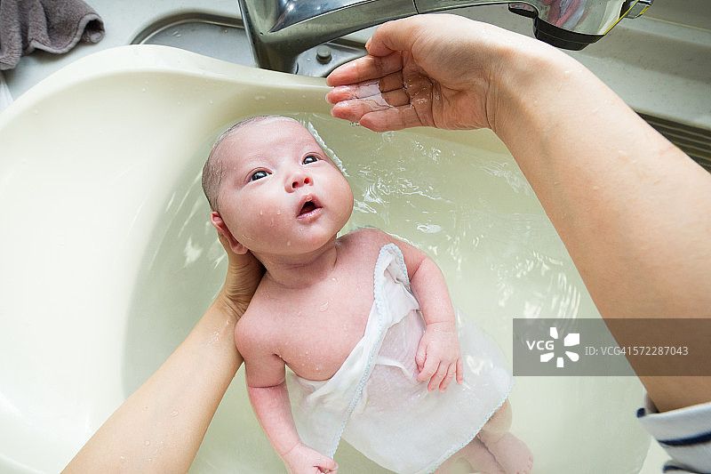 母亲们对给婴儿洗澡感到很兴奋图片素材