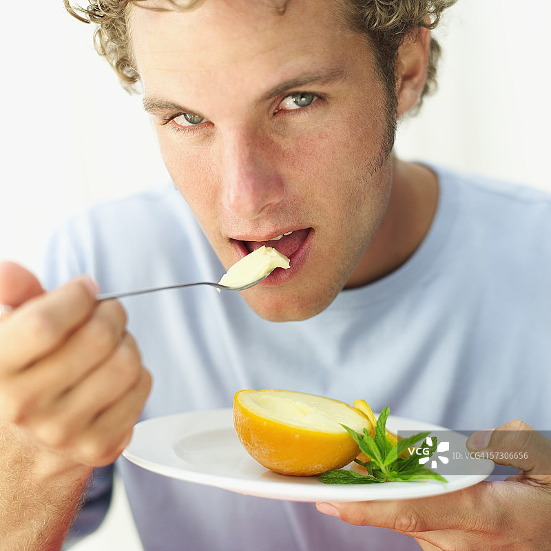 一个年轻人用勺子吃橘子冰沙的特写图片素材