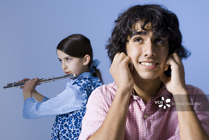 一个十几岁的女孩在一个十几岁的男孩后面吹长笛的特写图片素材