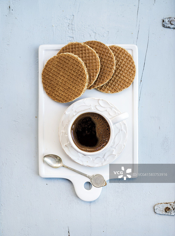 荷兰焦糖松饼和一杯黑咖啡，白色陶瓷餐盘，浅蓝色木质背景图片素材