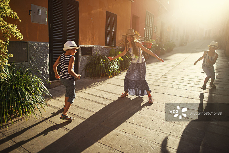 孩子们在地中海的街道上玩捉人游戏。图片素材