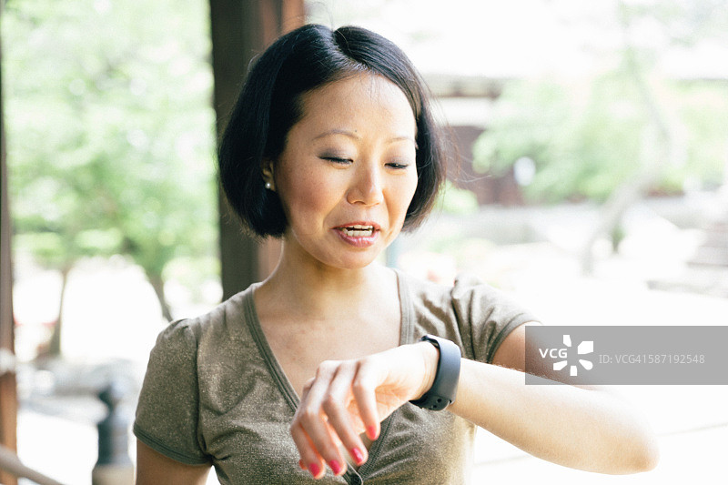 日本开朗的女人在户外使用智能手表图片素材